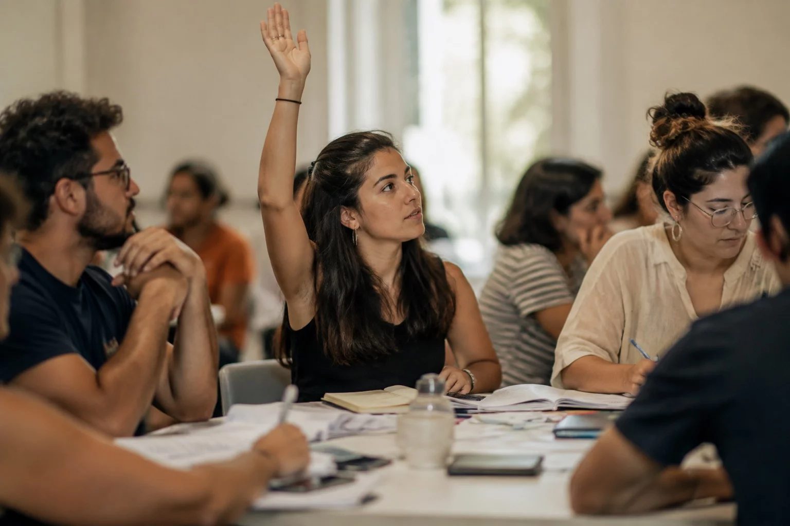 Estudante levantando a mão em uma mesa de seminário coberta de anotações
