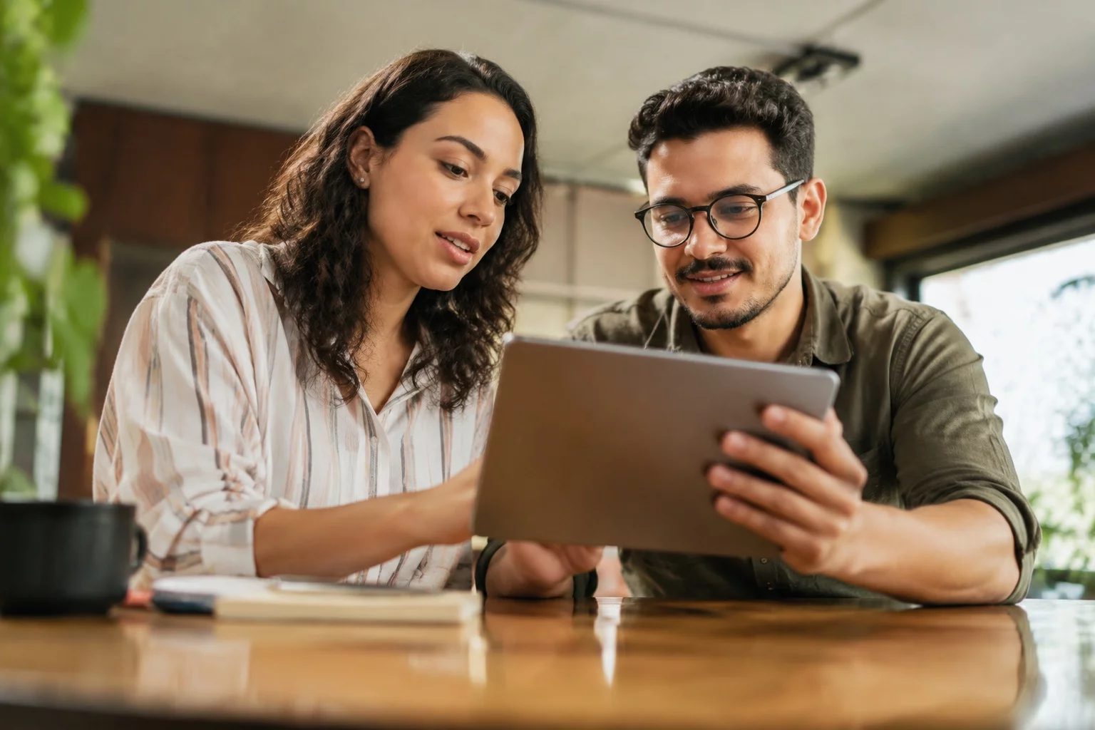 Duas pessoas revisando anotações em um tablet sobre uma mesa de madeira